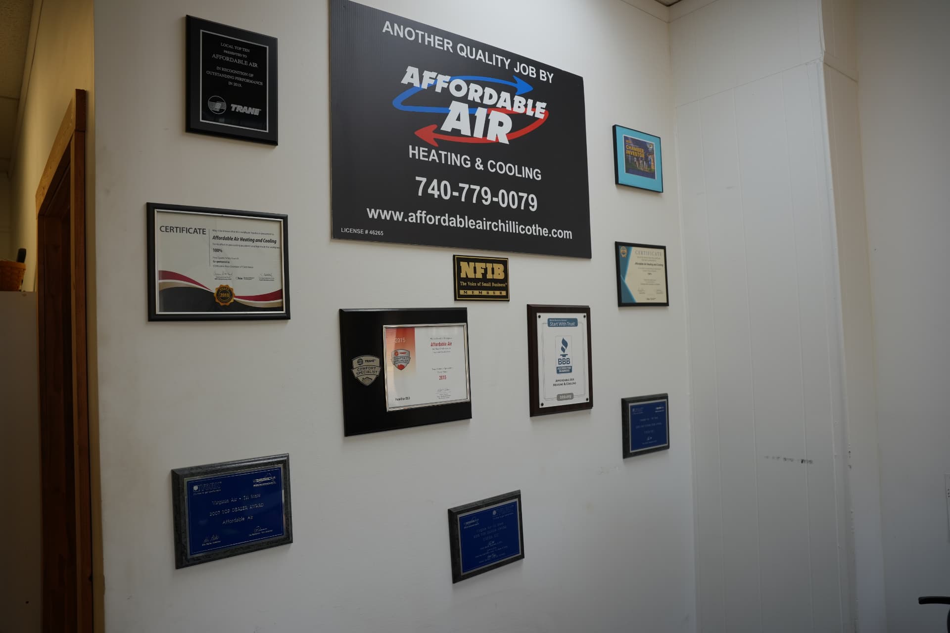 Affordable Air Heating & Cooling sign surrounded by Trane, BBB, NFIB and Chamber awards on the shop wall