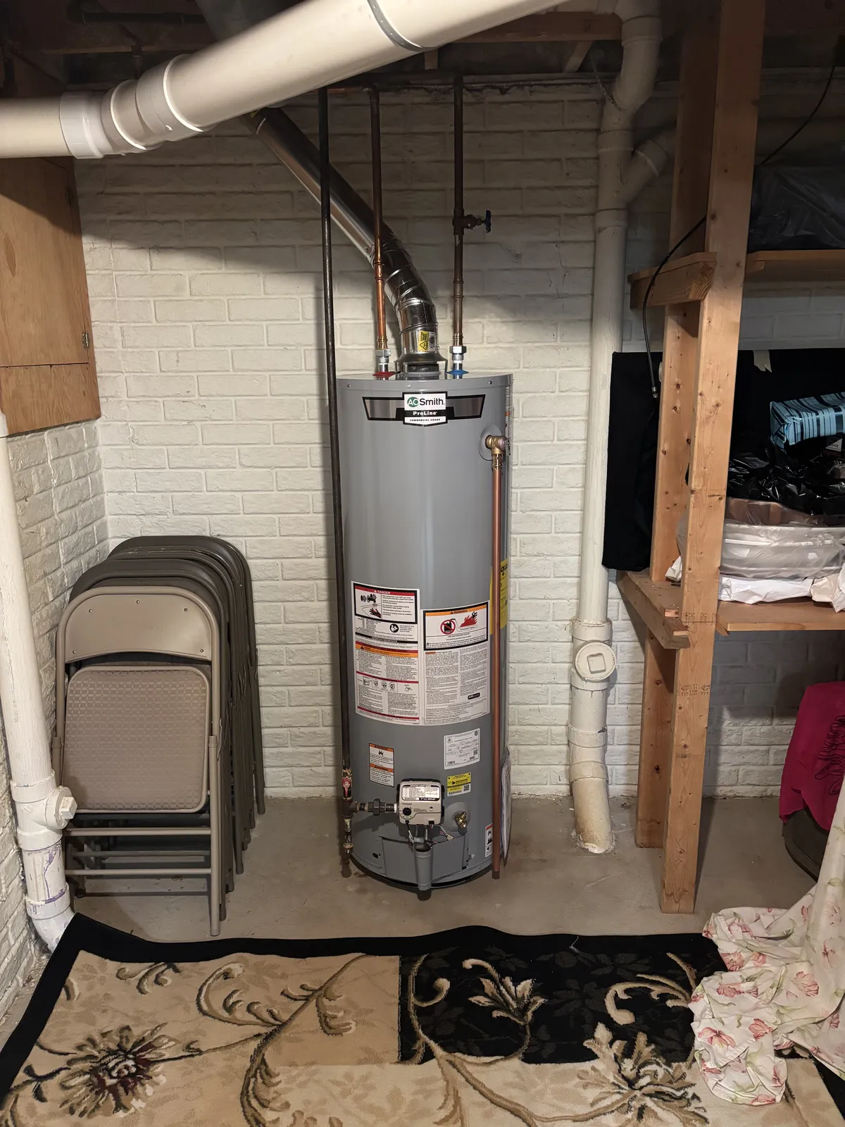 A newly installed A.O. Smith gas tank water heater with copper water lines and venting in a basement
