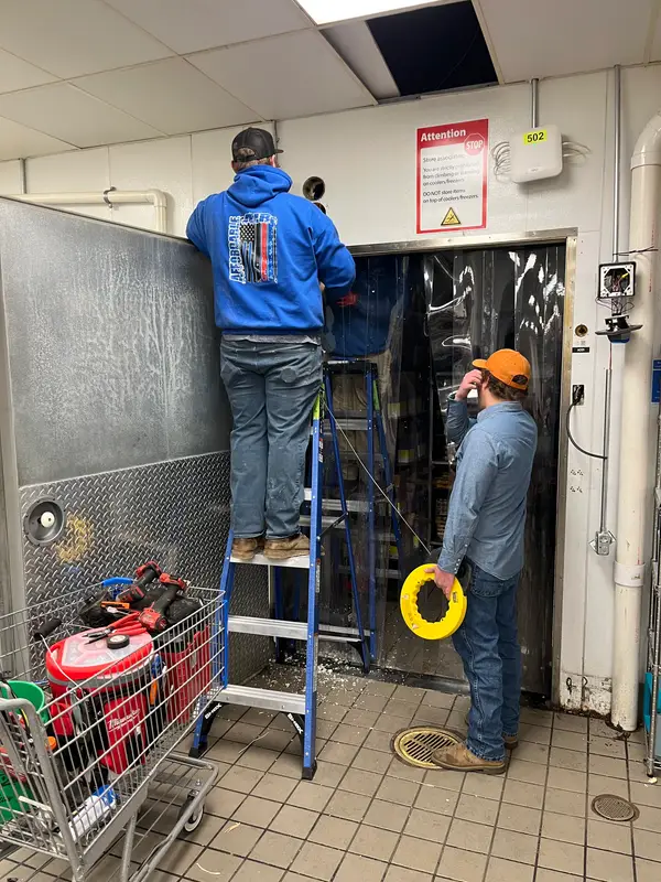 Two Affordable Air technicians servicing a commercial walk-in cooler